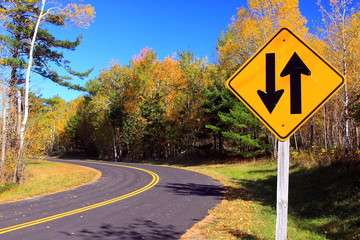 Two way sign with the road in autumn