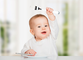 Funny baby with a knife and fork eating food