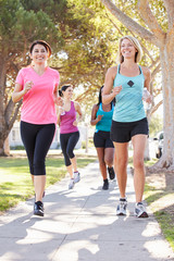 Group Of Female Runners Exercising On Suburban Street