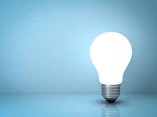 Light bulb standing on blue background with reflection