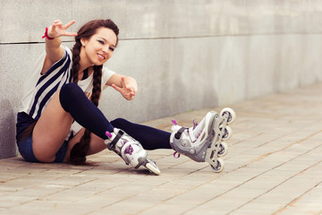 happy teenager on rollerblading sitting on street