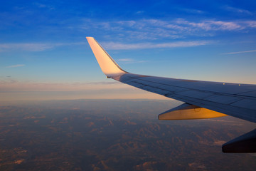 Obraz premium Airplane jet wing at sunset with golden sunlight
