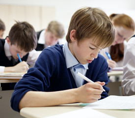 school boy struggling to finish test in class.