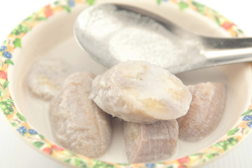 Banana in coconut milk on metal spoon show Thai dessert