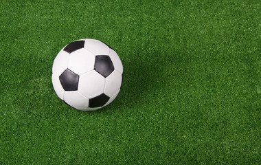Black and white football or soccer ball, green gridiron