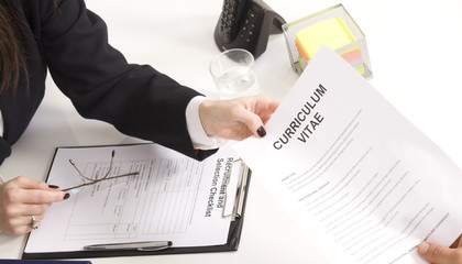 man at a a job interview with  interviewer, giving her his resum