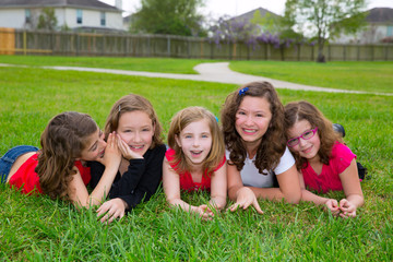 Children girls group lying on lawn grass smiling happy