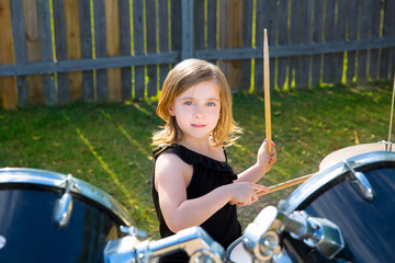 Drummer blond kid girl playing drums in tha backyard