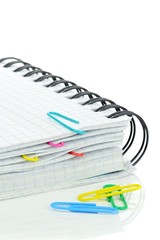 A spiral notebook and coloured paperclips on white background