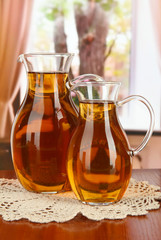 Apple juice in pitchers on table in room