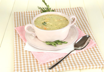 Nourishing soup in pink pan on wooden table close-up