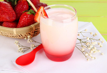 Delicious strawberry yogurt in glass on wooden table close-up