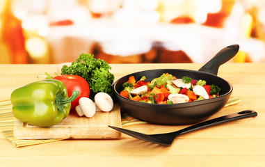Vegetable ragout in pan,  on wooden table on bright background