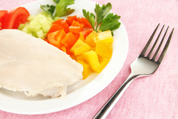 Boiled chicken breast on plate with vegetables close up