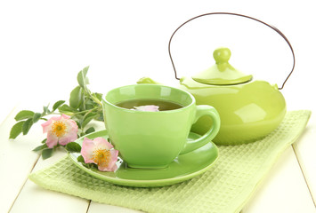 Cup and teapot of herbal tea with hip rose flowers
