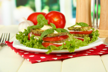 Tasty roasted marrow and tomato slices with salad leaves,