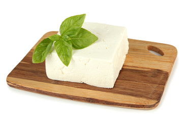 Sheep milk cheese with basil on cutting board, isolated on
