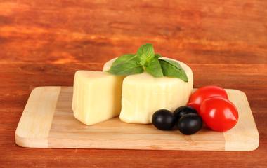 Cheese mozzarella,basil and vegetables on wooden background