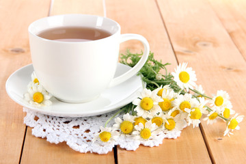 Cup of chamomile tea and chamomile on wooden table