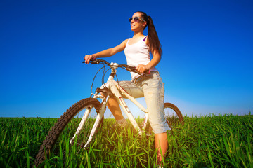 woman in a green field on a bike