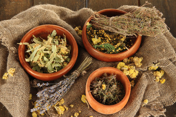 Medicinal Herbs in wooden bowls on bagging close-up