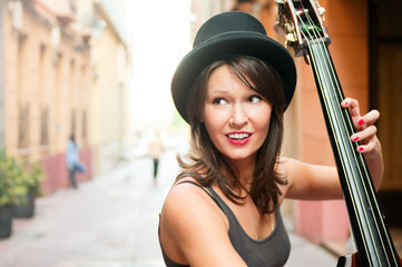 Woman in hat playing double bass on the street