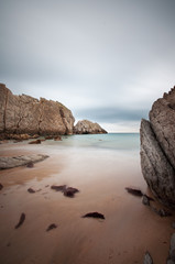 long exposure on a beach full of rocks with cloudy sky