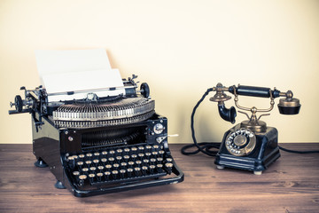 Vintage telephone, old typewriter on table