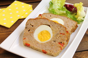 Sliced meatloaf with boiled egg and red pepper