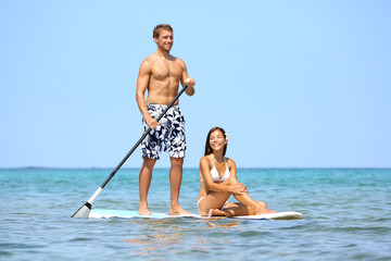 Beach fun couple on stand up paddleboard