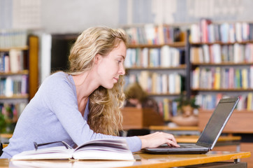 female student with laptop working in library