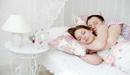 Fototapeta na wymiar Embracing young couple sleeping on the bed