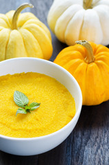 Pumpkin porridge and pumpkins on black wooden table