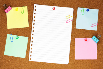 Colourful blank note paper on brown corkboard