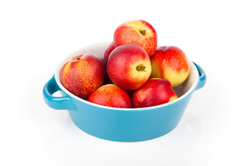 red ripe nectarine peaches on bowl,  isolated on white