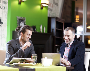 Two men in suits at restaurant cheerfully talk