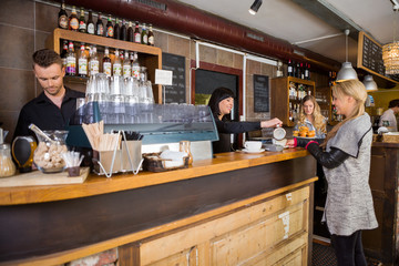 Female Bartender Serving Coffee To Customer At Counter