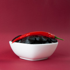 Lakritzschnecken mit Chili auf rotem Hintergrund