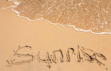 word sunrise written in the sand