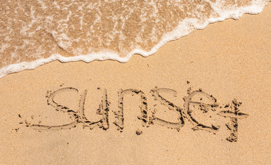 word sunset written in the sand