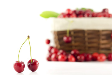 A pair of cherries with a basket in the background
