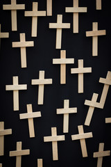 25 plain handmade wooden crosses suspended on a black canvas