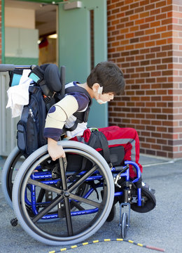 Disabled kindergartener in wheelchair on playground at recess