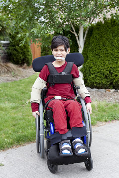Disabled little boy in wheelchair outdoors