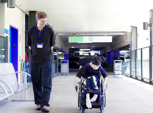Father walking with disabled son in wheelchair to the hospital