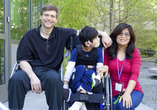 Disabled child in wheelchair with his parents
