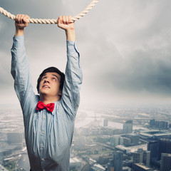 Businessman hanging on rope