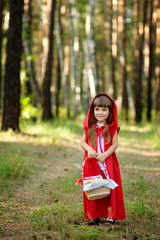 girl in the wood with a basket looking at camera.Red Riding Hood