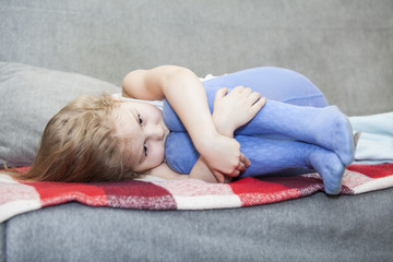 Small Caucasian defenseless child huddled on the couch