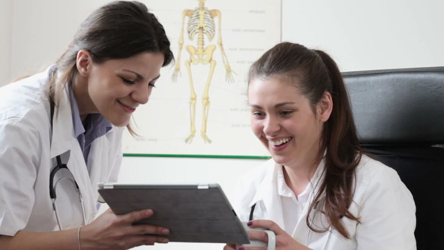 Two happy female doctors with tablet computer